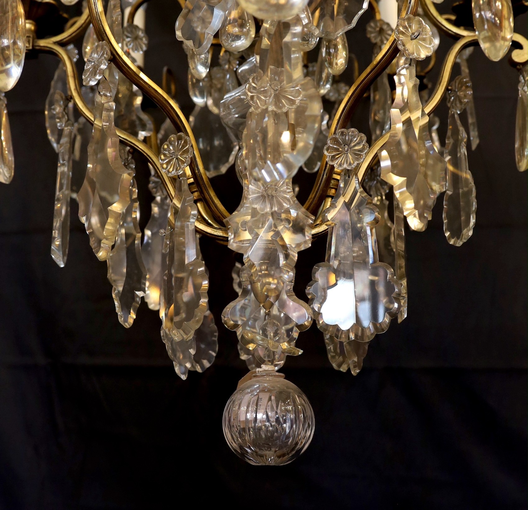 An early 20th century French bronze and cut glass twelve light chandelier, hung with tear, lozenge and flowerhead shaped drops, drop 114cm. width 72cm